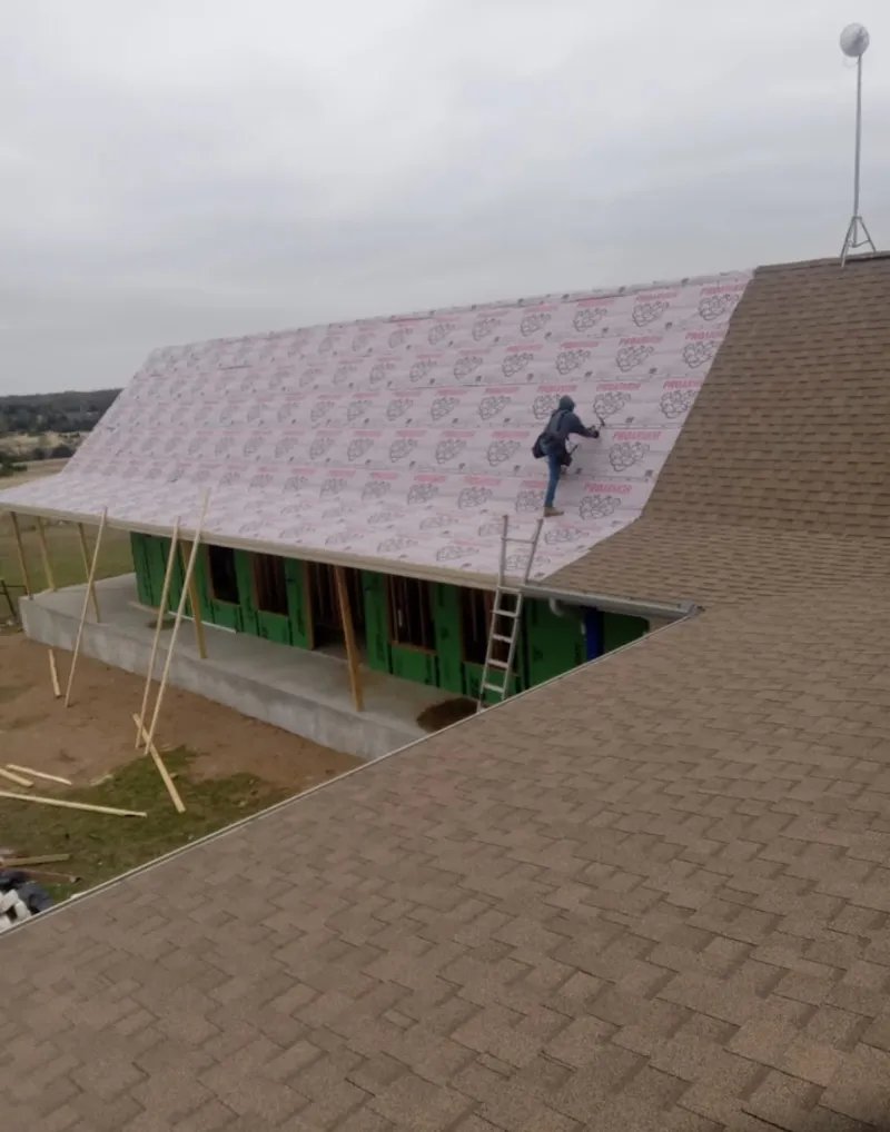 Worker preparing underlayment for a metal roof installation in Simsbury